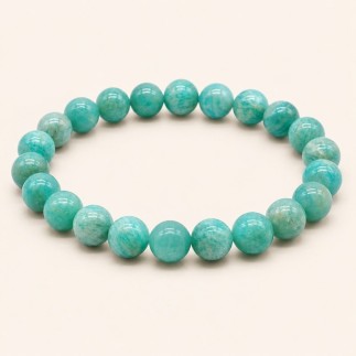 Bracelet en amazonite à perles rondes de 8 mm, aux nuances vert bleuté et aux marbrures claires, sur fond beige.