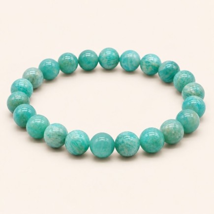 Bracelet en amazonite à perles rondes de 8 mm, aux nuances vert bleuté et aux marbrures claires, sur fond beige.