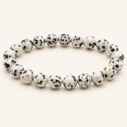 Bracelet en jaspe dalmatien à perles rondes de 8 mm, crème tachetées de noir, présenté sur fond beige clair.