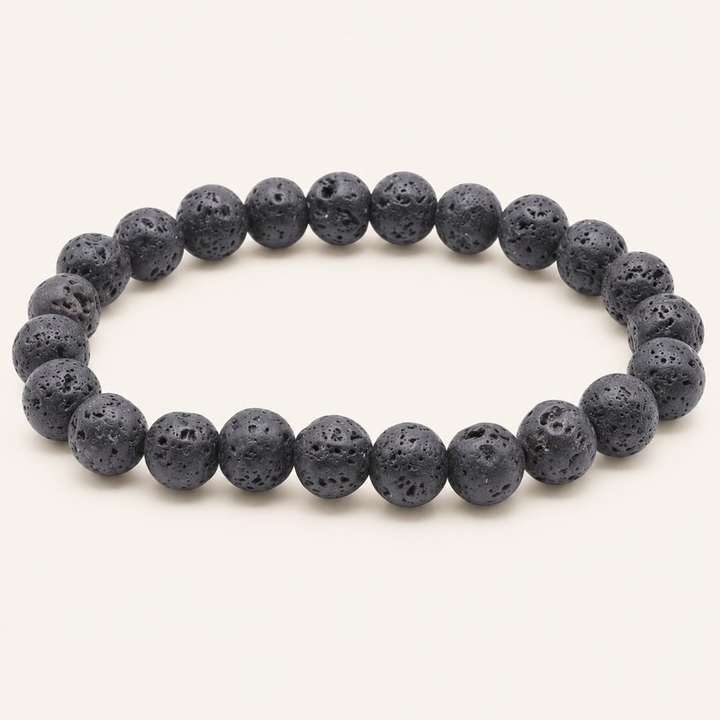 Bracelet en pierre de lave à perles rondes de 8 mm, gris anthracite à noires et poreuses, présenté sur fond beige clair.
