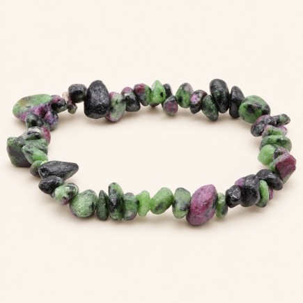 Bracelet baroque en rubis-zoïsite aux pierres polies vertes, noires et rose violacé, présenté sur fond beige clair.