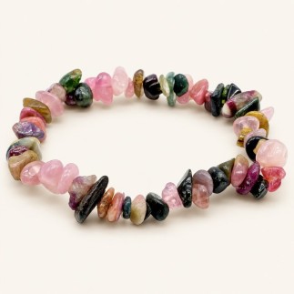 Bracelet baroque en tourmaline multicolore aux pierres polies roses, vertes, sombres et ocre, présenté sur fond beige clair.