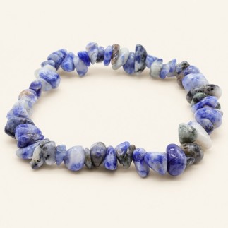 Bracelet baroque en sodalite aux pierres polies bleues, blanches et grises, présenté sur fond beige clair.