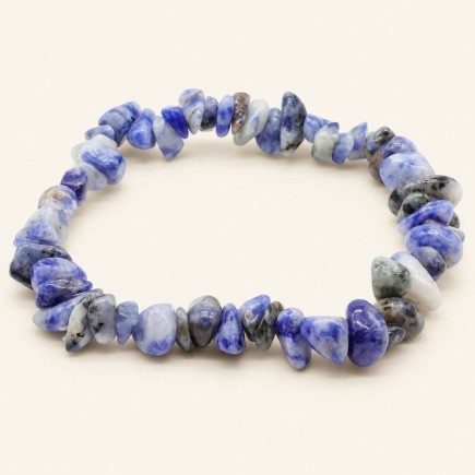 Bracelet baroque en sodalite aux pierres polies bleues, blanches et grises, présenté sur fond beige clair.