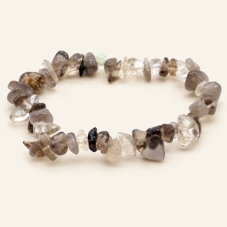 Bracelet baroque en quartz fumé aux pierres polies grises, brunes et très claires, présenté sur fond beige clair.