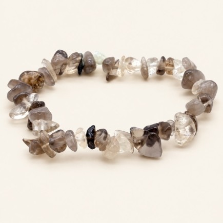 Bracelet baroque en quartz fumé aux pierres polies grises, brunes et très claires, présenté sur fond beige clair.