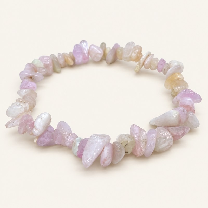 Bracelet baroque en kunzite aux pierres polies rose pâle, lilas, blanchâtres et crème, présenté sur fond beige clair.
