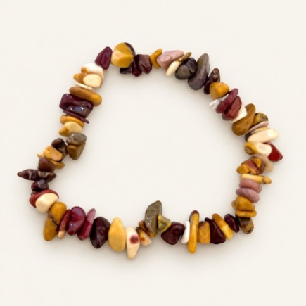 Bracelet baroque en jaspe mokaïte aux pierres polies ocre, bordeaux, crème et brunes, présenté sur fond beige clair.