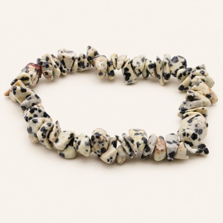 Bracelet baroque en jaspe dalmatien aux pierres polies crème et beige tachetées de noir, présenté sur fond beige clair.