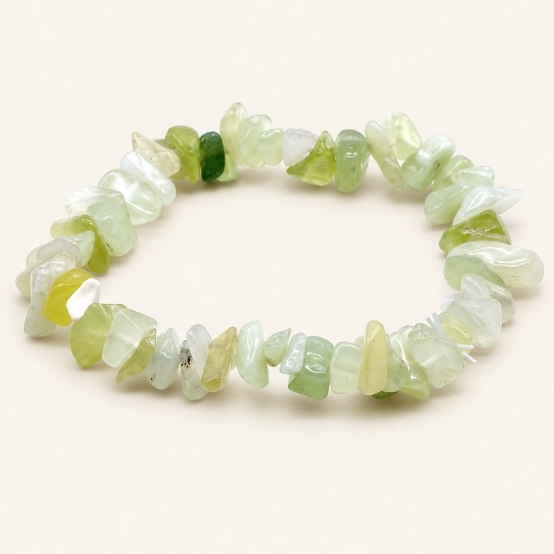 Bracelet baroque en jade vert aux pierres polies vert pâle, blanchâtres et jaune-vert, présenté sur fond beige clair.