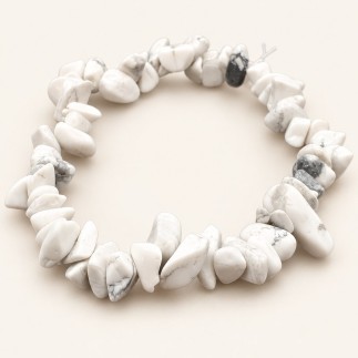 Bracelet baroque en howlite aux pierres polies blanches à ivoire, parcourues de veinures grises, présenté sur fond beige clair.