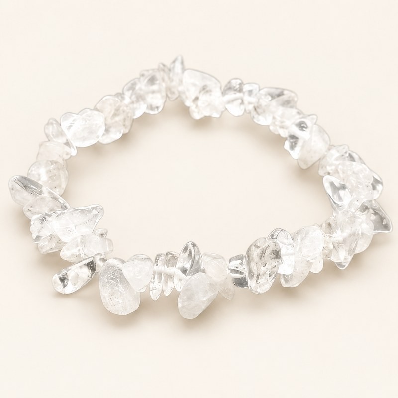 Bracelet baroque en cristal de roche aux pierres chips transparentes et voilées, présenté sur fond beige.
