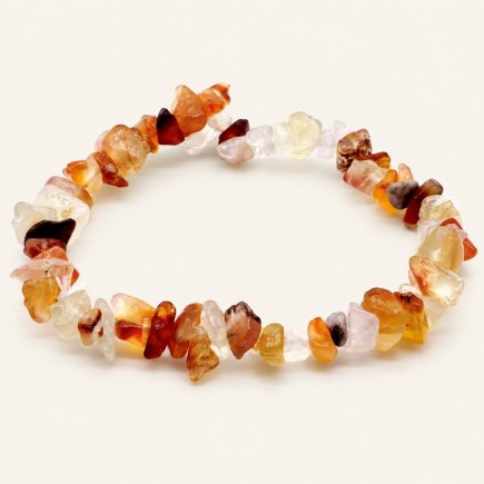 Bracelet baroque en cornaline aux pierres chips orangées, miel, rouge brun et très claires, présenté sur fond beige.