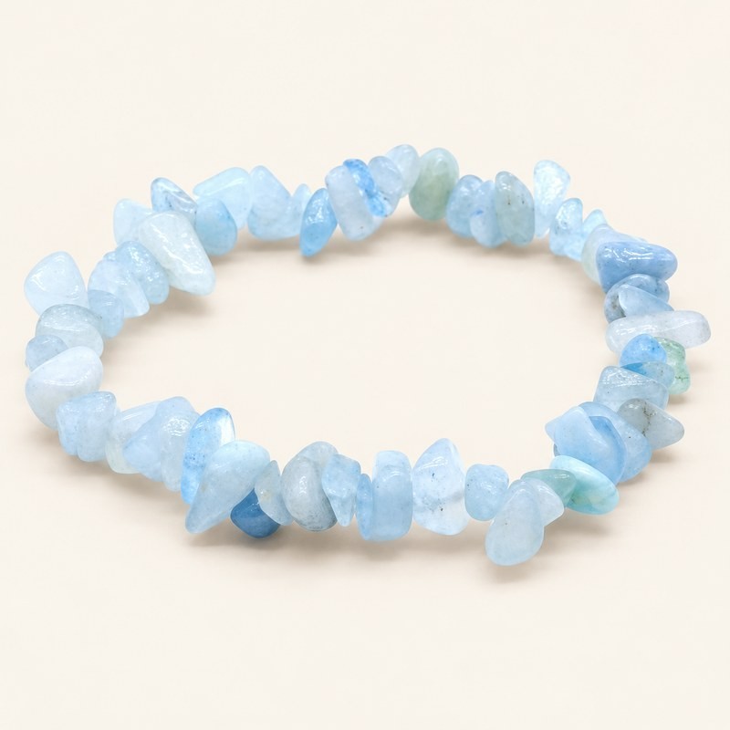 Bracelet baroque en aigue-marine aux pierres chips bleu pâle et laiteuses, présenté sur fond beige.