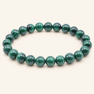 Bracelet en malachite de Zambie, perles rondes de 8 mm aux bandes vert clair et vert foncé, sur fond beige.