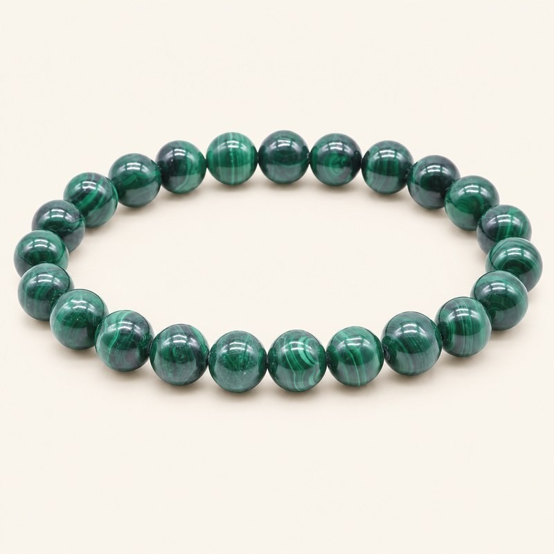 Bracelet en malachite de Zambie, perles rondes de 8 mm aux bandes vert clair et vert foncé, sur fond beige.