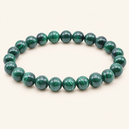 Bracelet en malachite de Zambie, perles rondes de 8 mm aux bandes vert clair et vert foncé, sur fond beige.