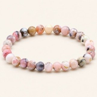 Bracelet en opale rose du Pérou, perles rondes de 8 mm aux nuances roses et crème avec des marques sombres, sur fond beige.