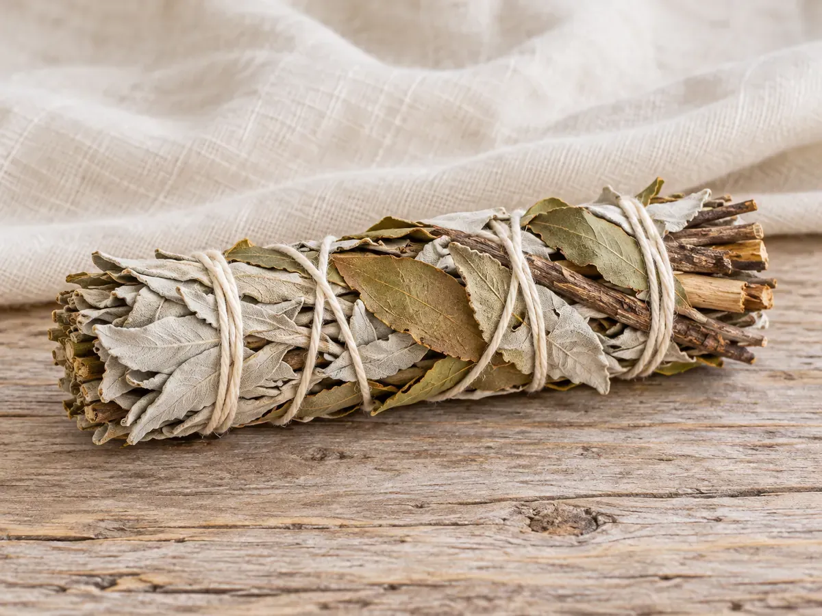 Fagot composé de sauge blanche, de feuilles et de bois de copal, maintenu par un lien.